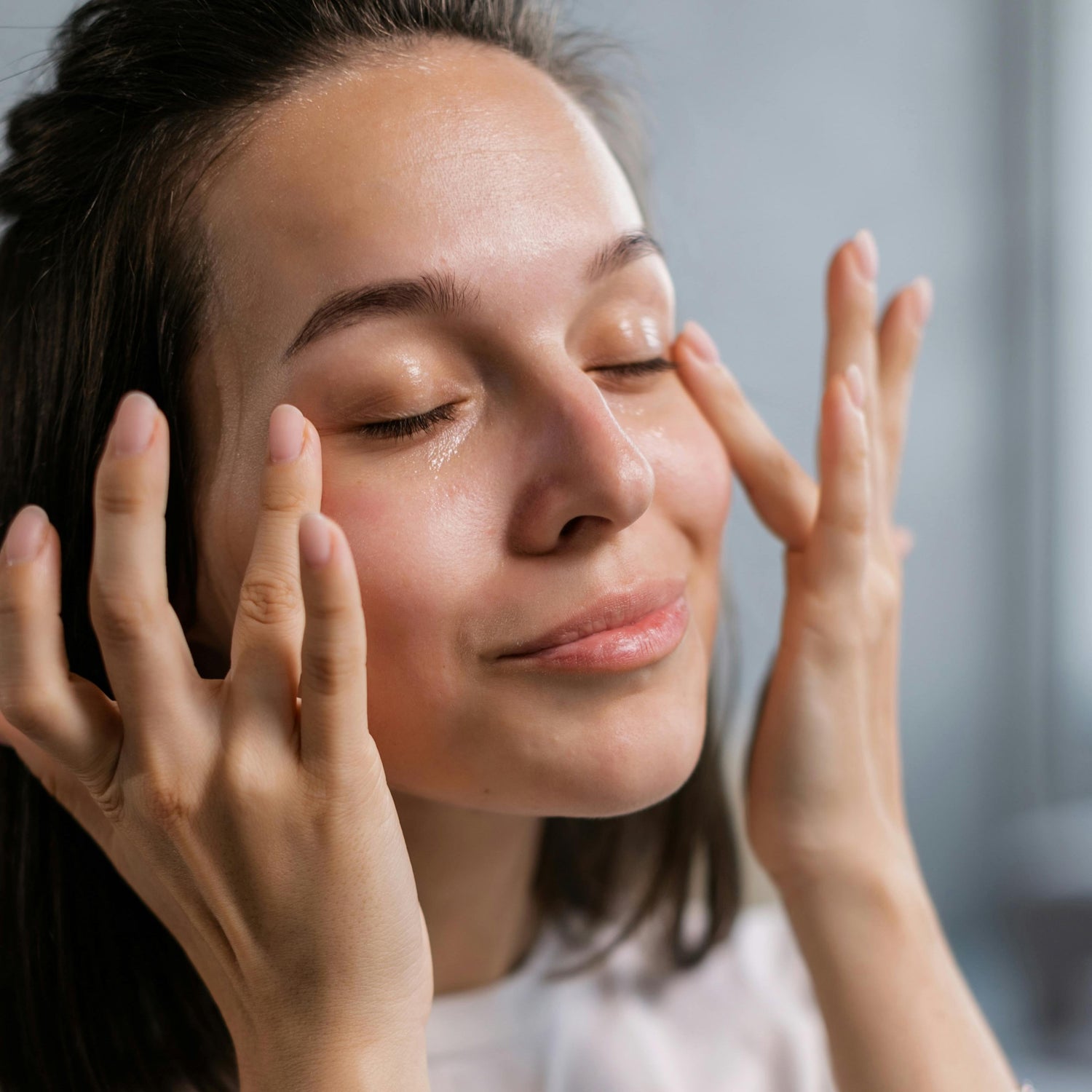 Femme qui se masse le visage avec une huile de soin